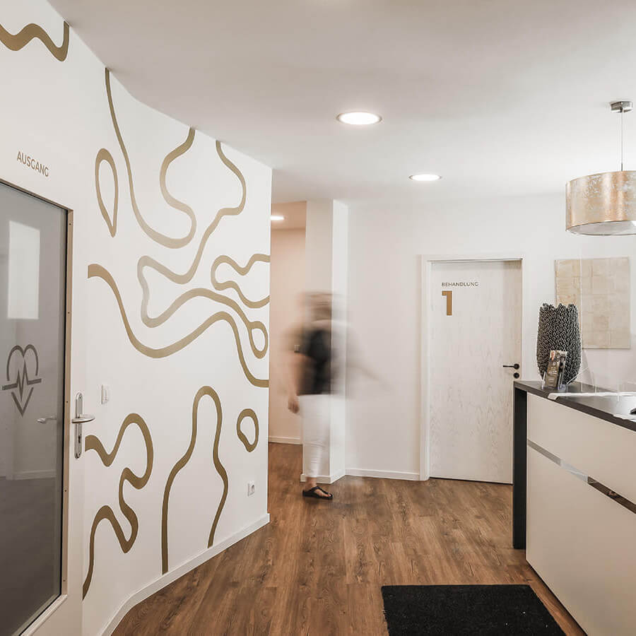 Blick auf den Empfangsbereich einer modernen Arztpraxis mit Empfangstheke und Behandlungszimmer