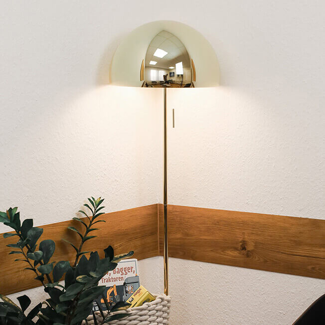 Ecke im Wartezimmer mit goldener Stehlampe, Pflanze und Kinderbüchern